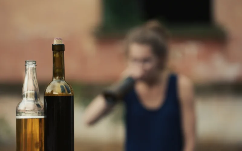 A lady drinking from a large bottle of Alcohol