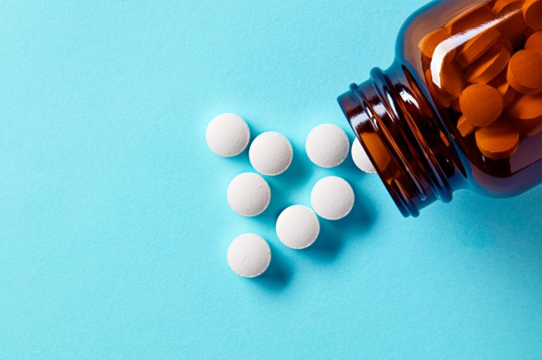 White medical pills that are cocodamol spilling from a bottle
