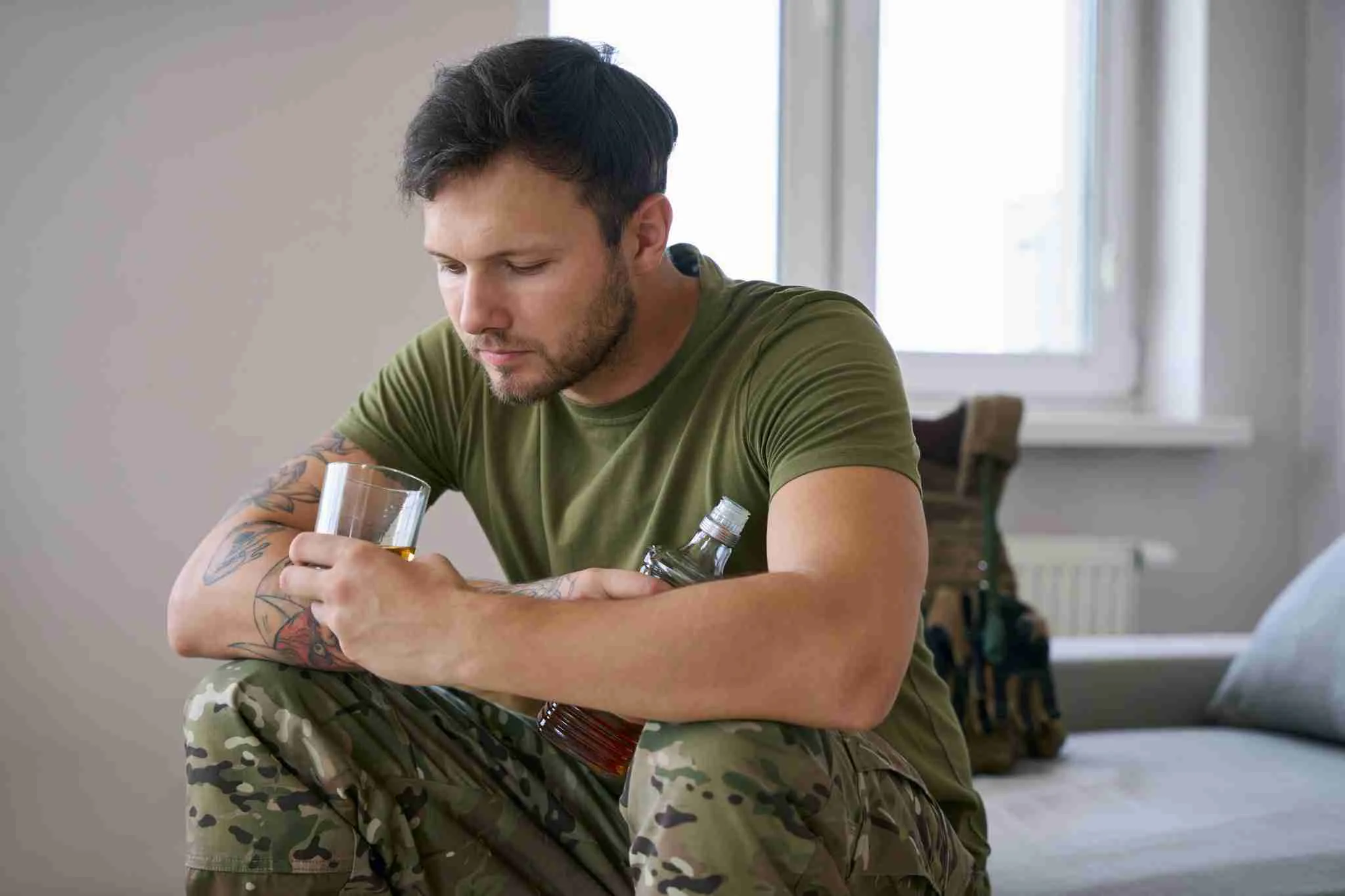 A soldier looking into a bottle as they duffer with PTSD and alcohol addiction