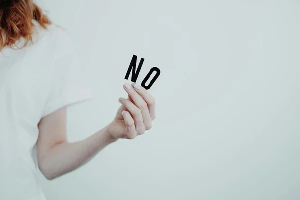 A person holding a sign that says no