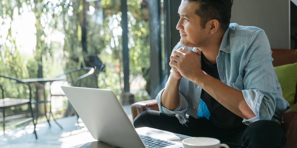 Asian,Handsome,Man,Sitting,Happily,Looking,Out,Of,The,Window Man looking out of the window as he sorts his finances
