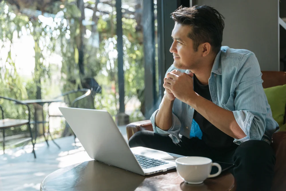 Man looking out of the window as he sorts his finances