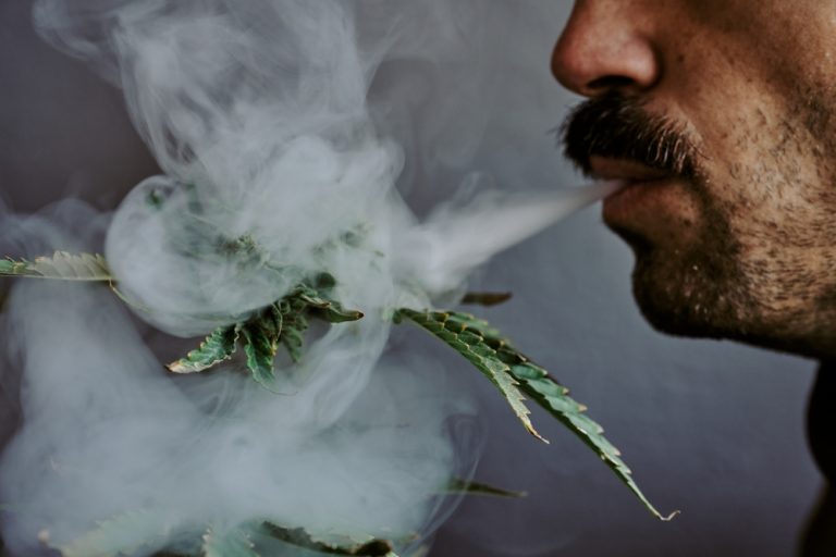 Individual blowing smoke on a plant