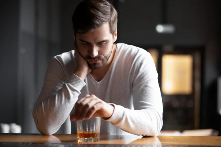 Man sat drinking alone looking sad, hiding his alcoholism