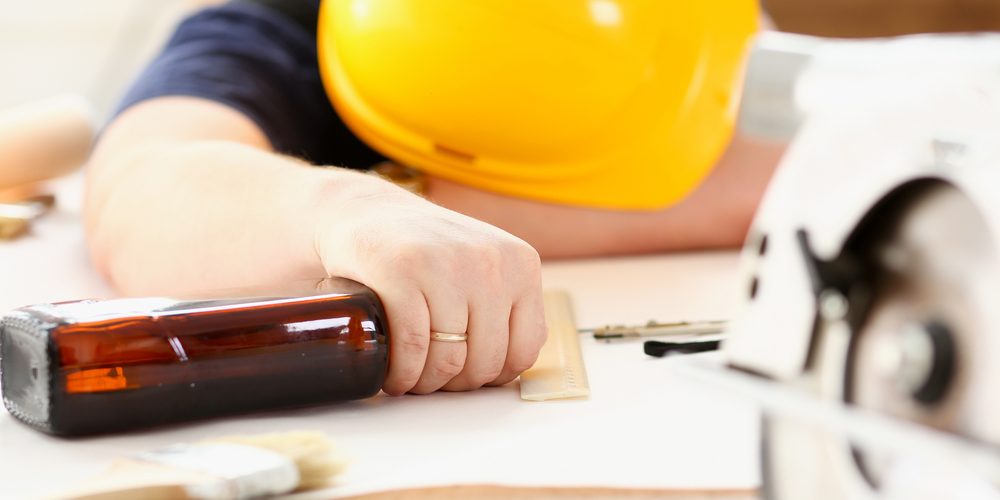 Arm,Of,Drunken,Worker,In,Yellow,Helmet,Hold,Liquor,Bottle A drunk worker