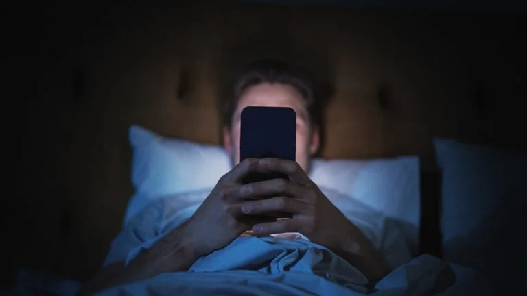 phone addiction shown with a person in bed on their phone