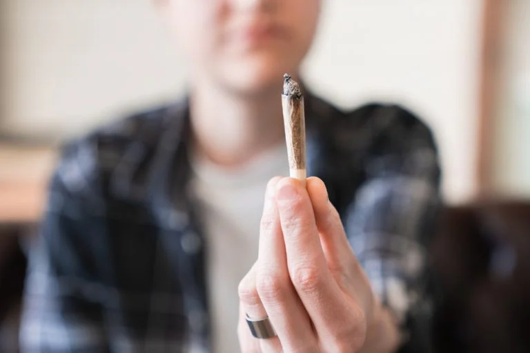 Individual holding a cannabis joint