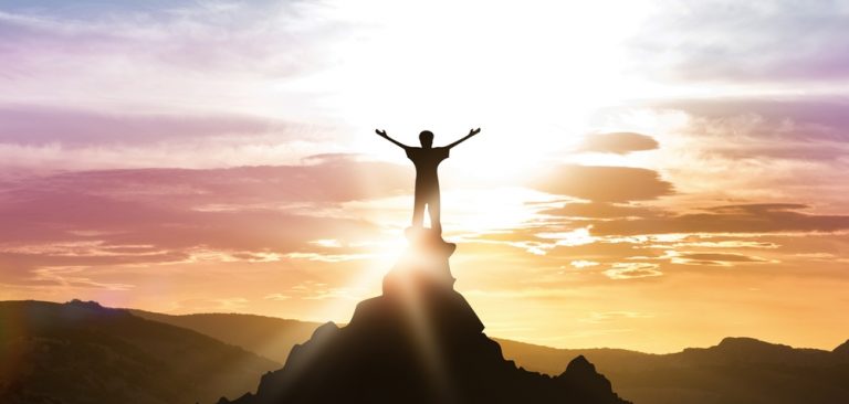 Man standing atop a mountain to show achievement