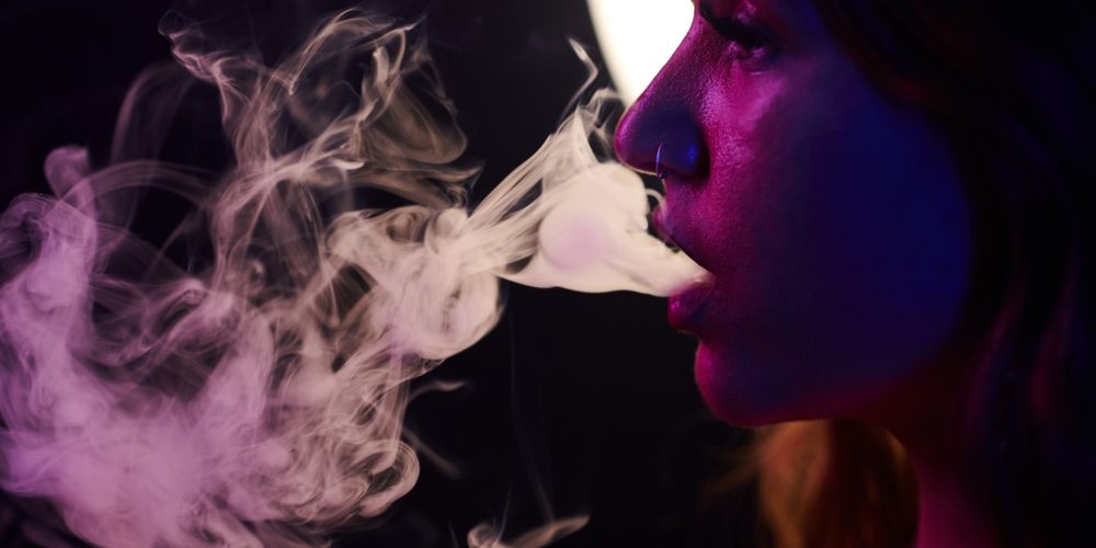 Young,Woman,In,Neon,Light,Exhaling,Smoke,Of,Electronic,Cigarette Vape being used for cannabis