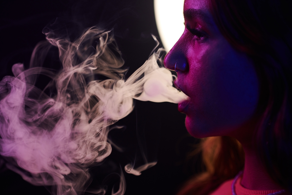 Young,Woman,In,Neon,Light,Exhaling,Smoke,Of,Electronic,Cigarette Vape being used for cannabis