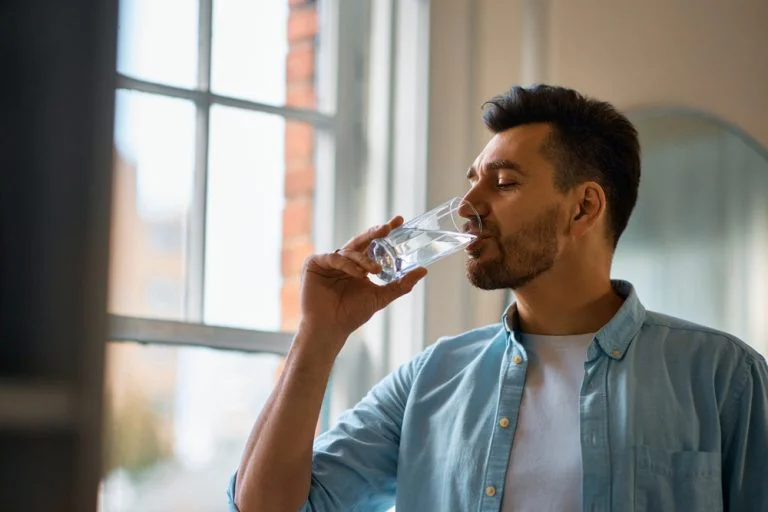 A man drinking water to help with a comedown
