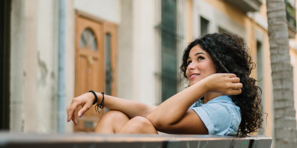 Smiling,Girl,With,Curly,Hair,And,Dress,Sitting,On,A Individual happy after rebuilding their life